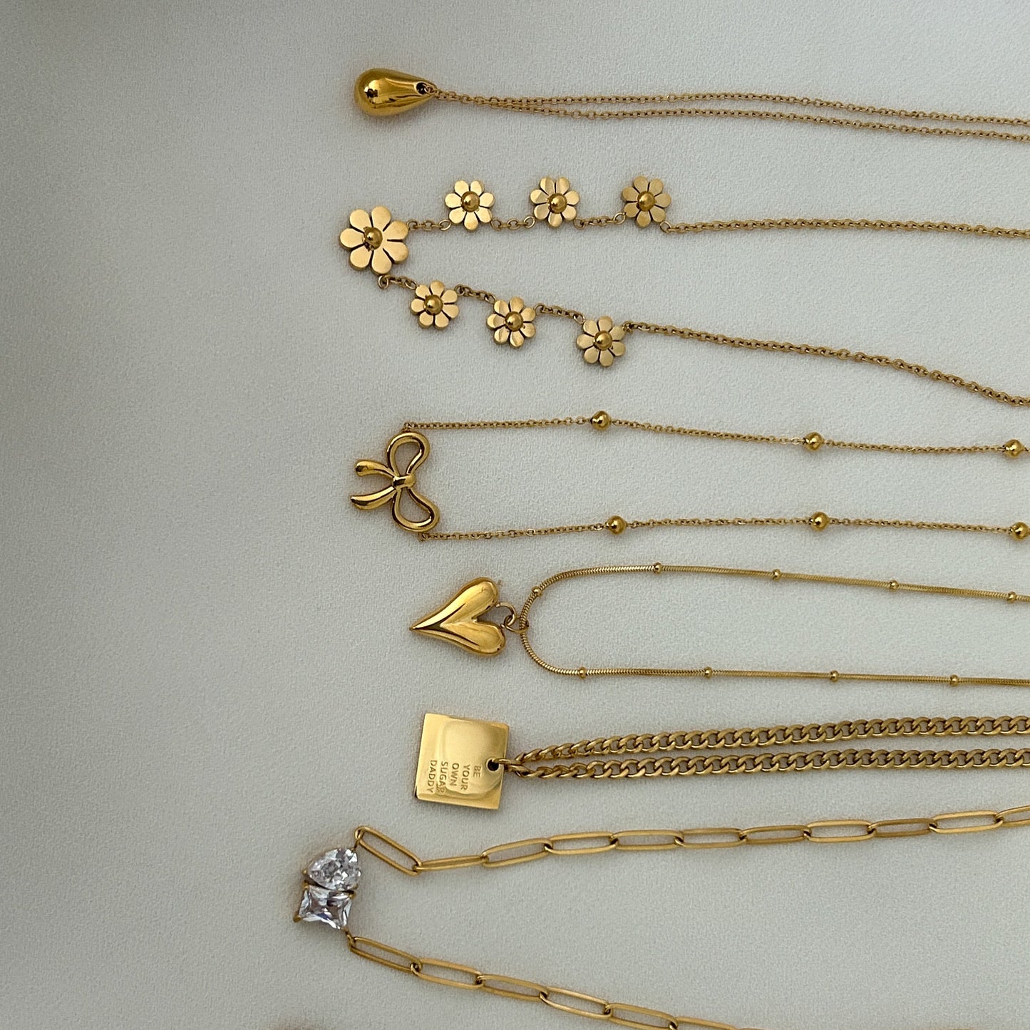 Collection of gold necklaces on a light gray background