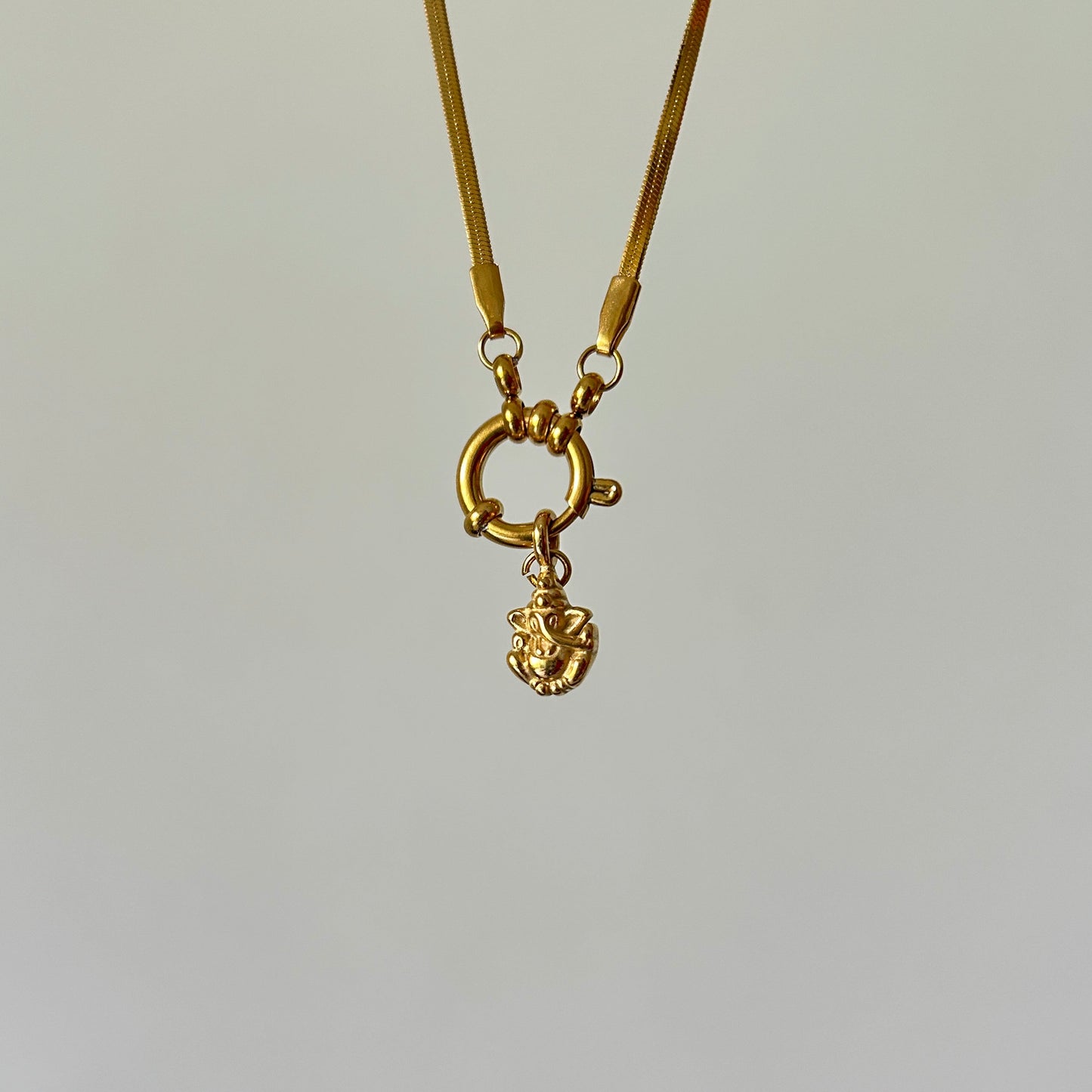 Gold necklace with a small pendant on a light gray background
