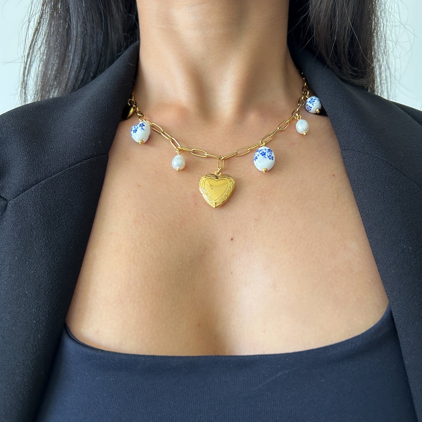 Necklace with a heart pendant worn by a person against a neutral background
