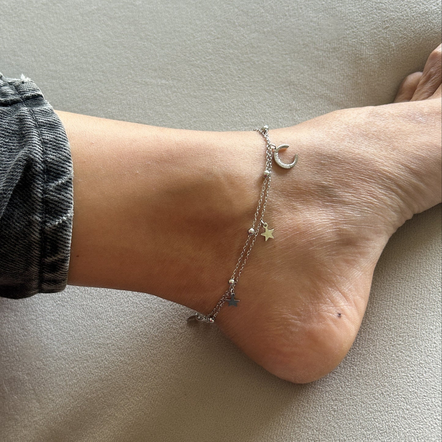 Close-up of a foot wearing a anklet on a neutral background