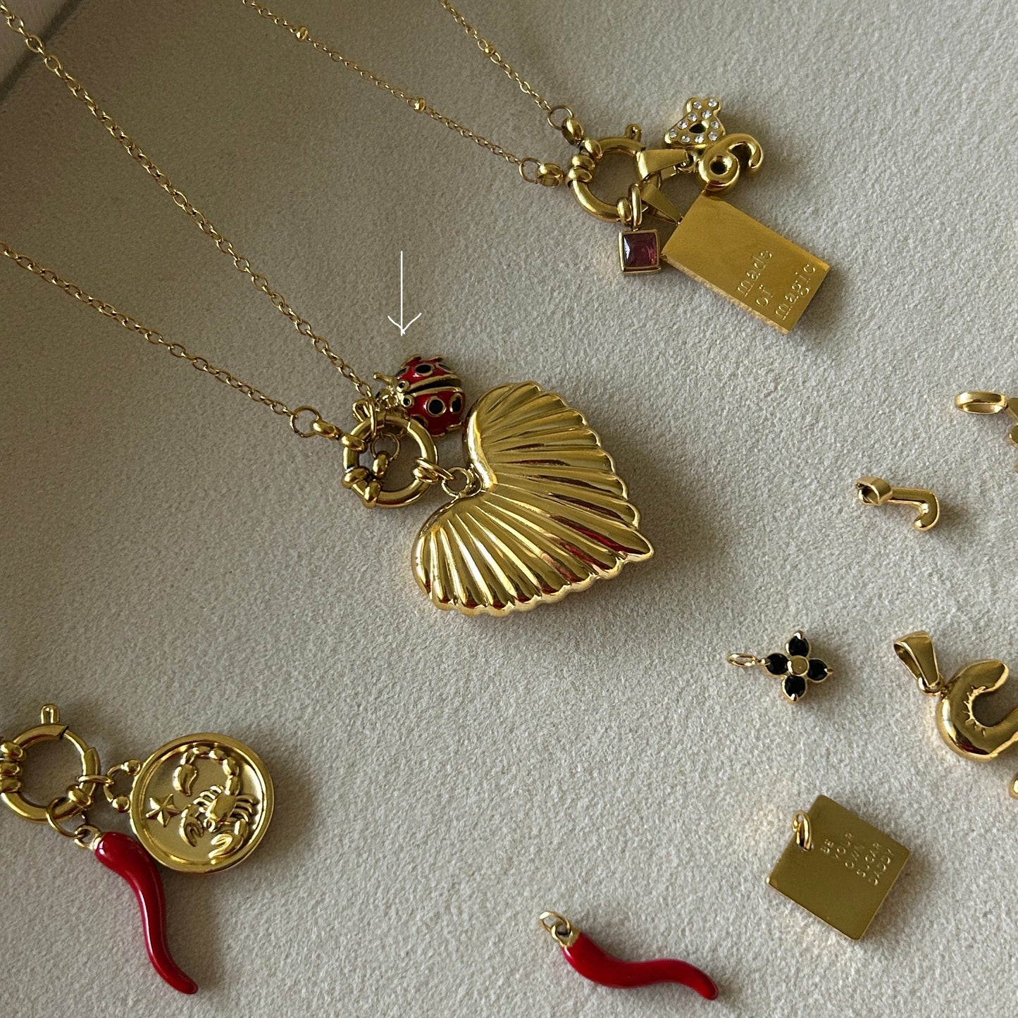 Gold jewelry charms and pendants on a light gray surface