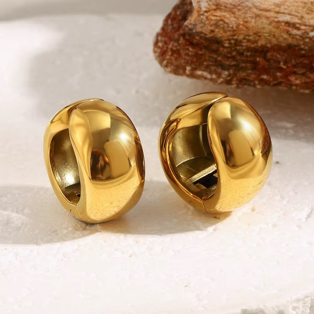 Pair of gold hoop earrings on a textured surface