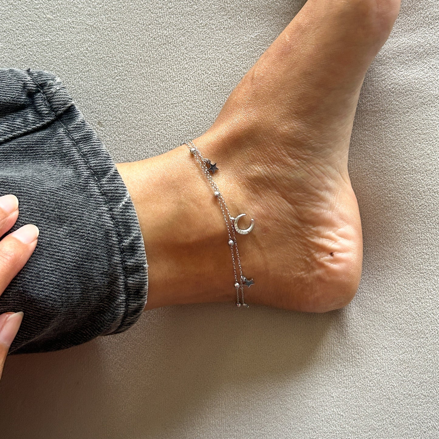Person wearing anklets on a neutral background