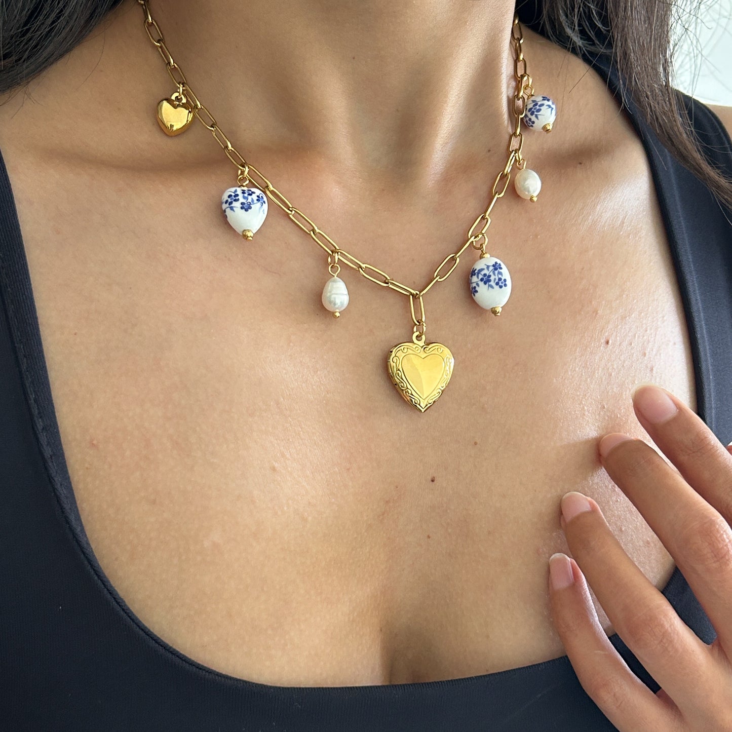 Necklace with heart and floral pendants on a person wearing a black top.