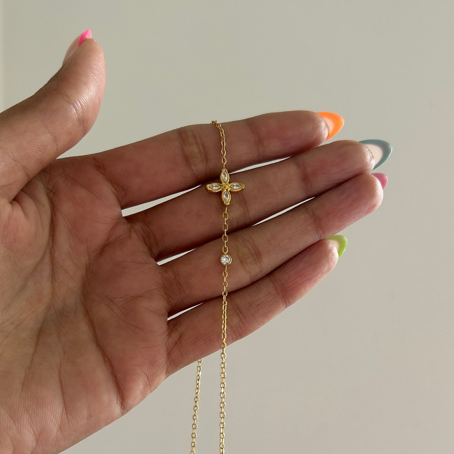 Hand wearing a gold bracelet on a plain background