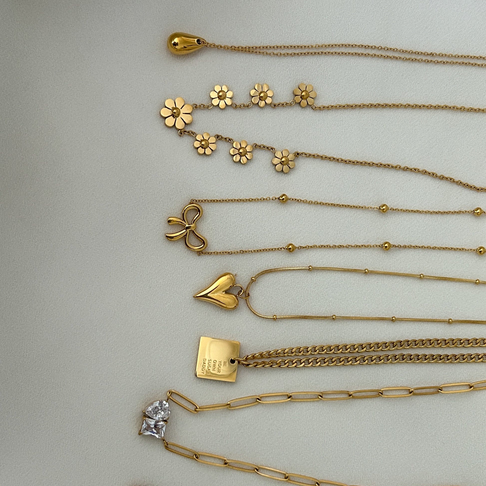 Collection of gold necklaces  on a light gray background