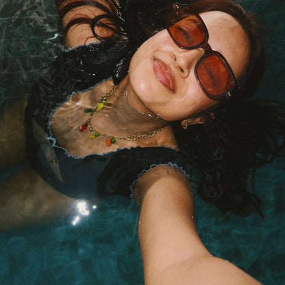 Person wearing Delta charms fruit charm necklace and a black swimsuit underwater