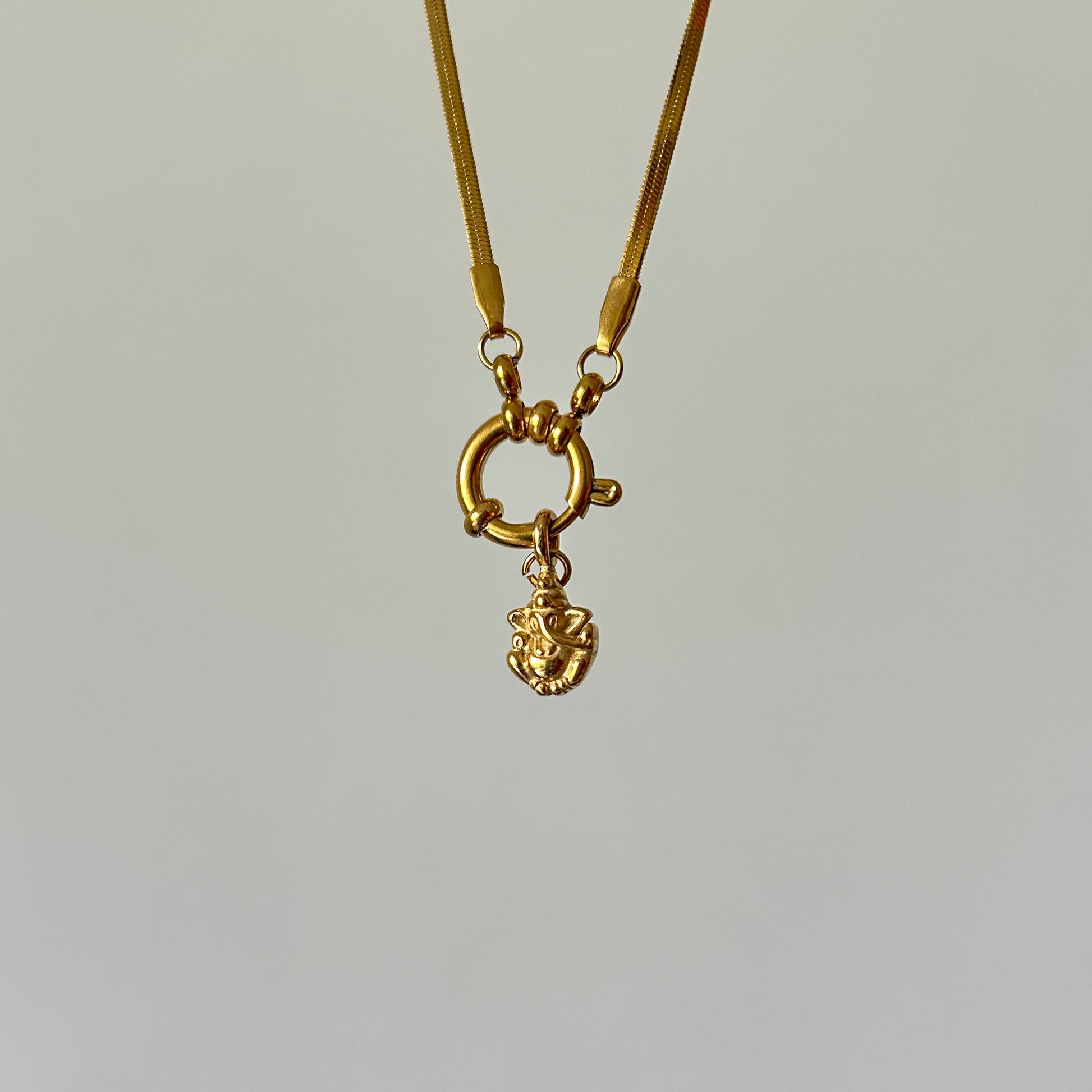 Gold necklace with a small pendant on a light gray background