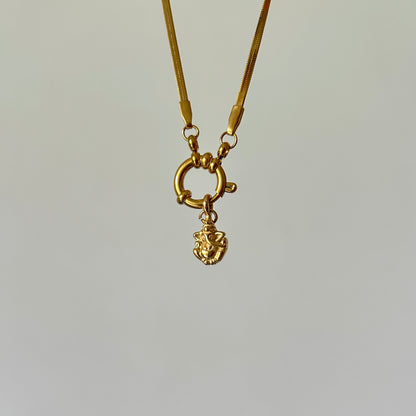 Gold necklace with a small pendant on a light gray background