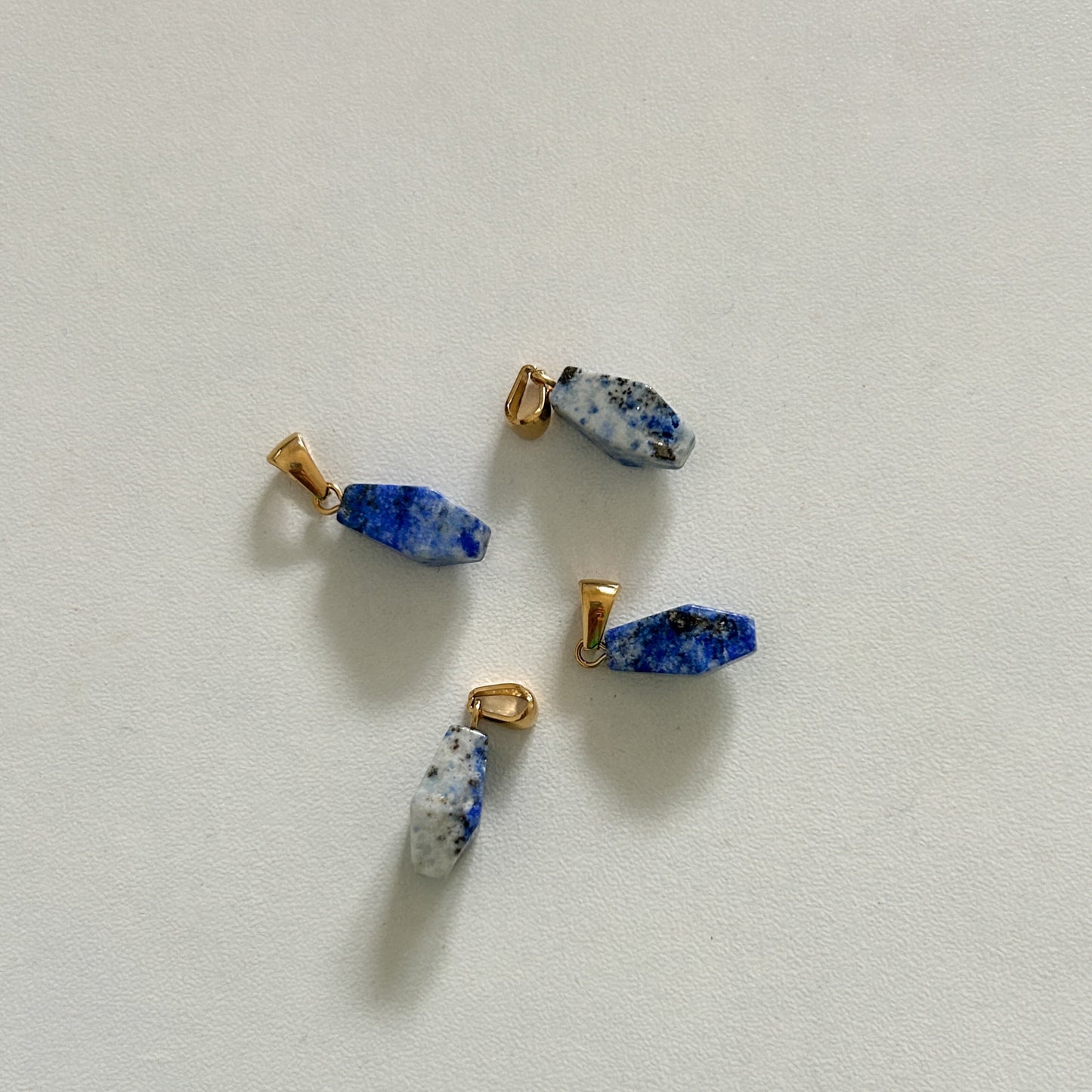 Three small blue lapis lazuli charm pieces on a white background