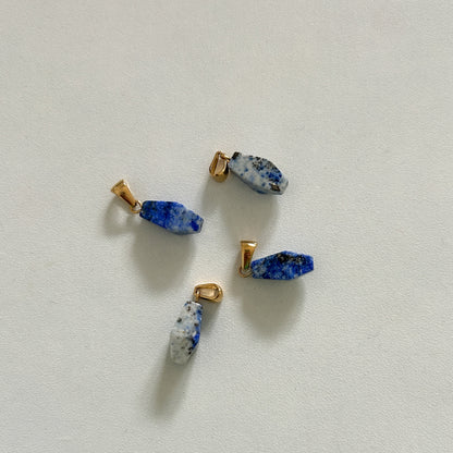 Three small blue lapis lazuli charm pieces on a white background