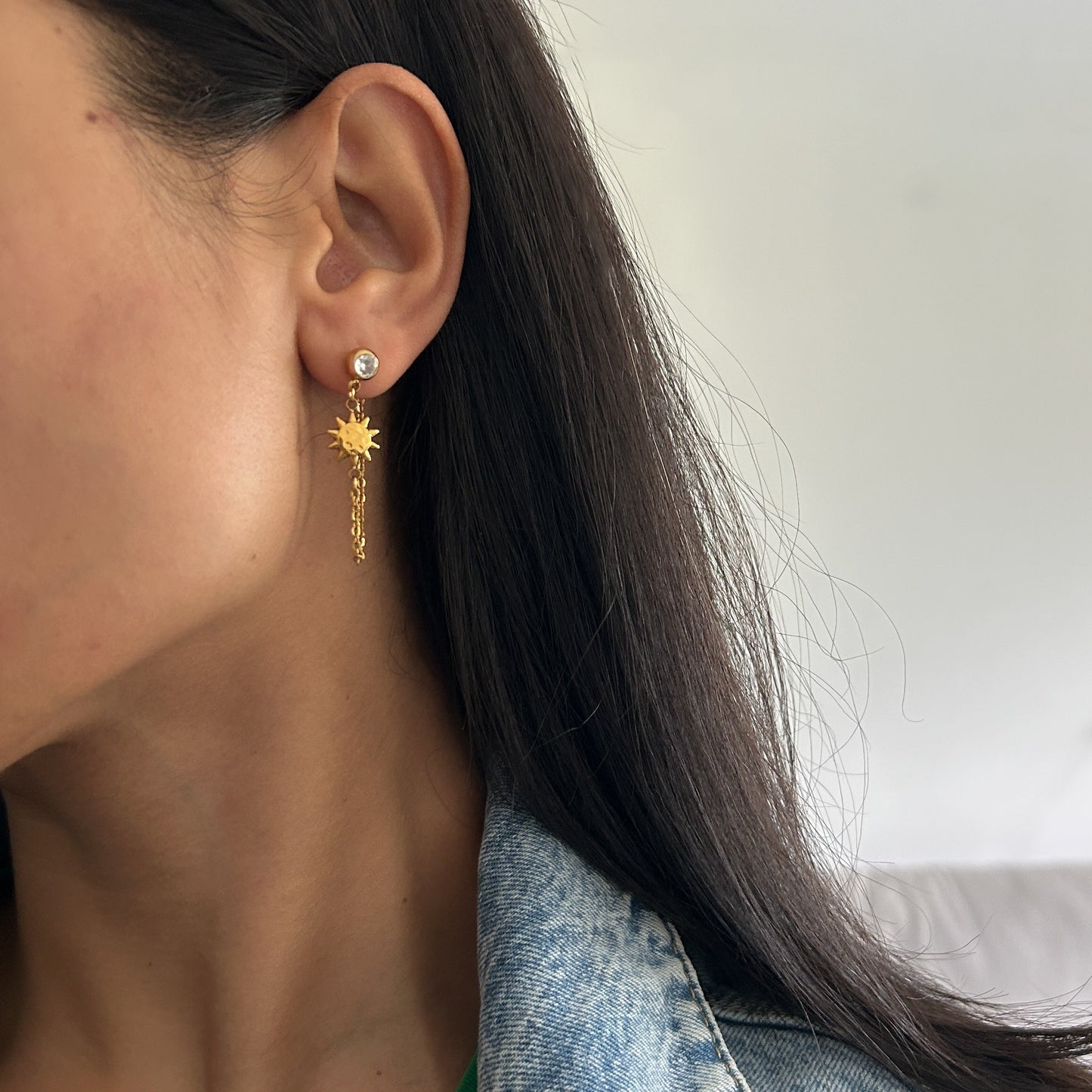 Close-up of a person wearing a sun-shaped earring with a blurred background