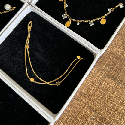Gold bracelets displayed in an open jewelry box on a wooden surface