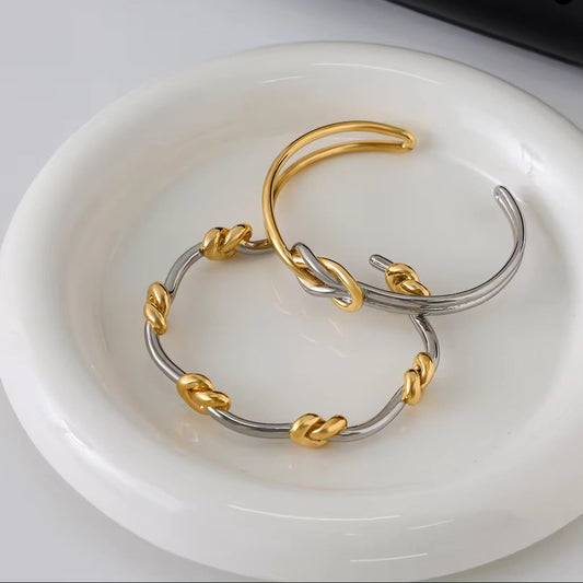Gold and silver cuff on a white dish with a black bag labeled 'GENTLE MONSTER' in the background.