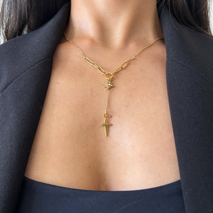 Gold necklace with a cross pendant worn by a person against a black background