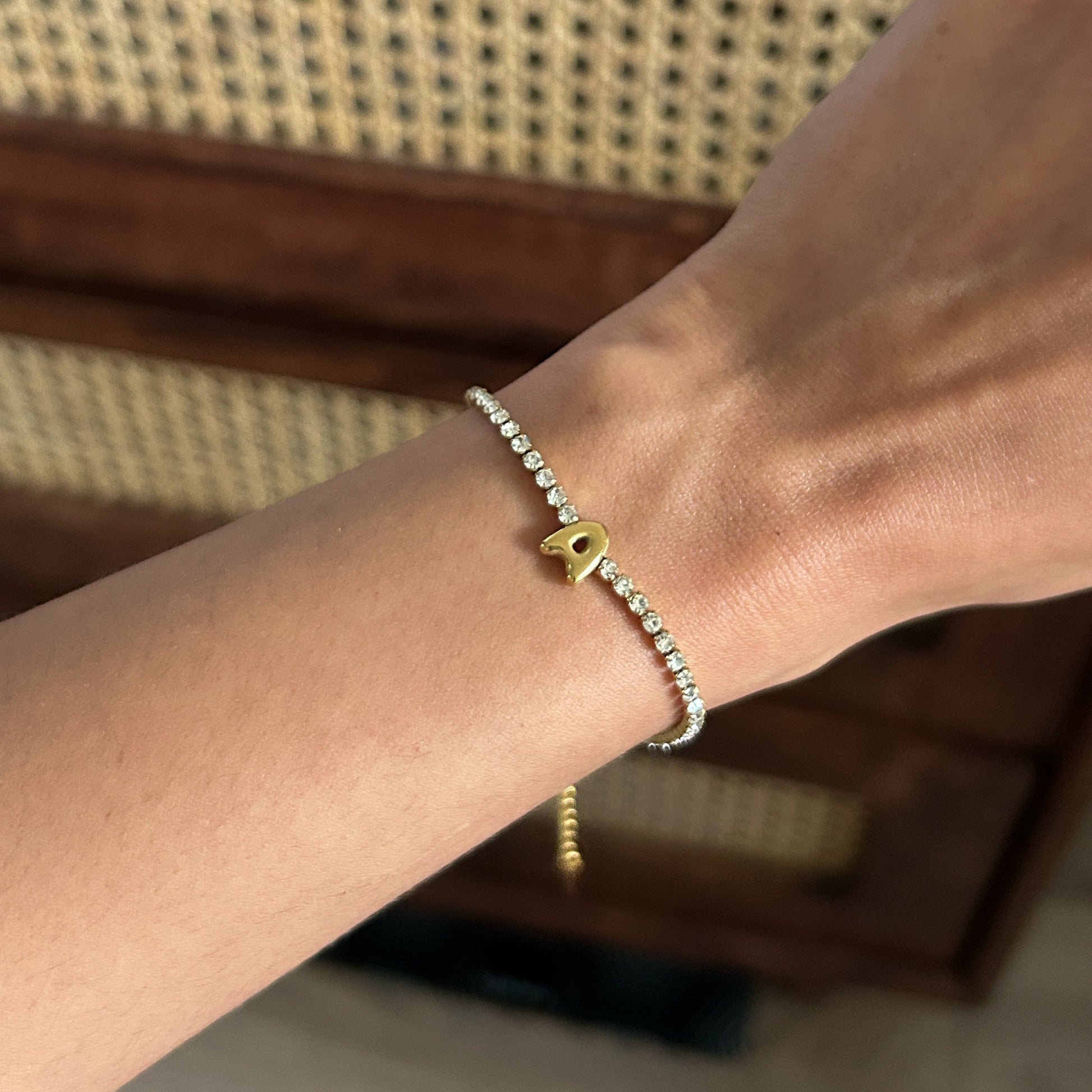 Bracelet with a small heart charm on a wrist against a blurred background