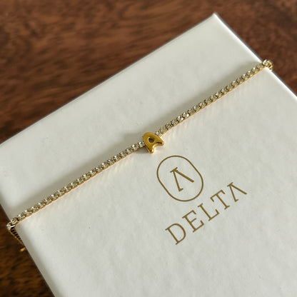 Gold bracelet on a white box with 'Delta' branding